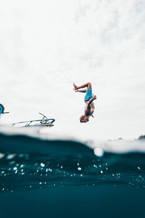 Guest backflipping off a charter boat into clear blue water
